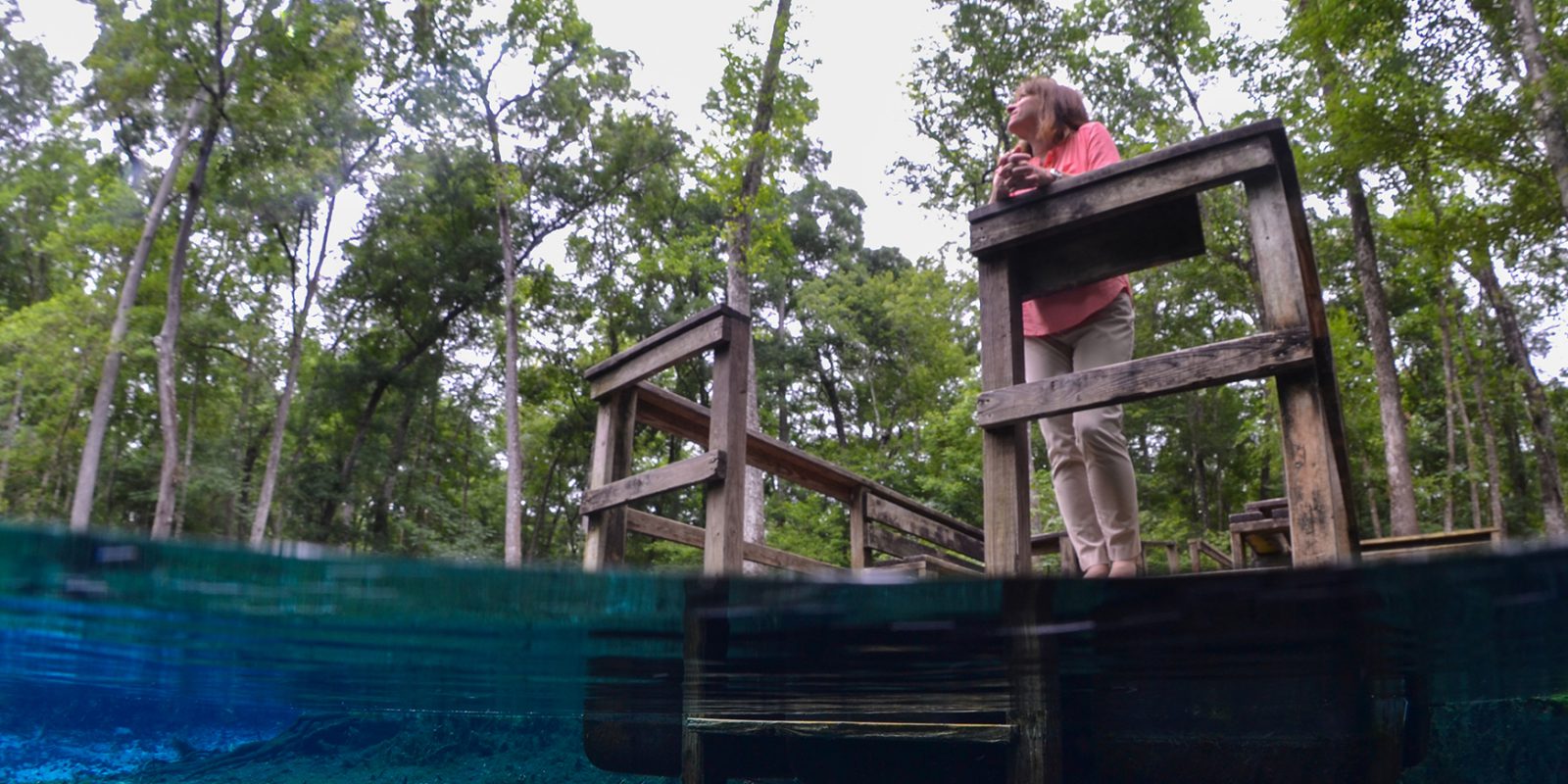 Photo taken with camera half-submerged in water of Dr. Graham looking out over the water from a dock