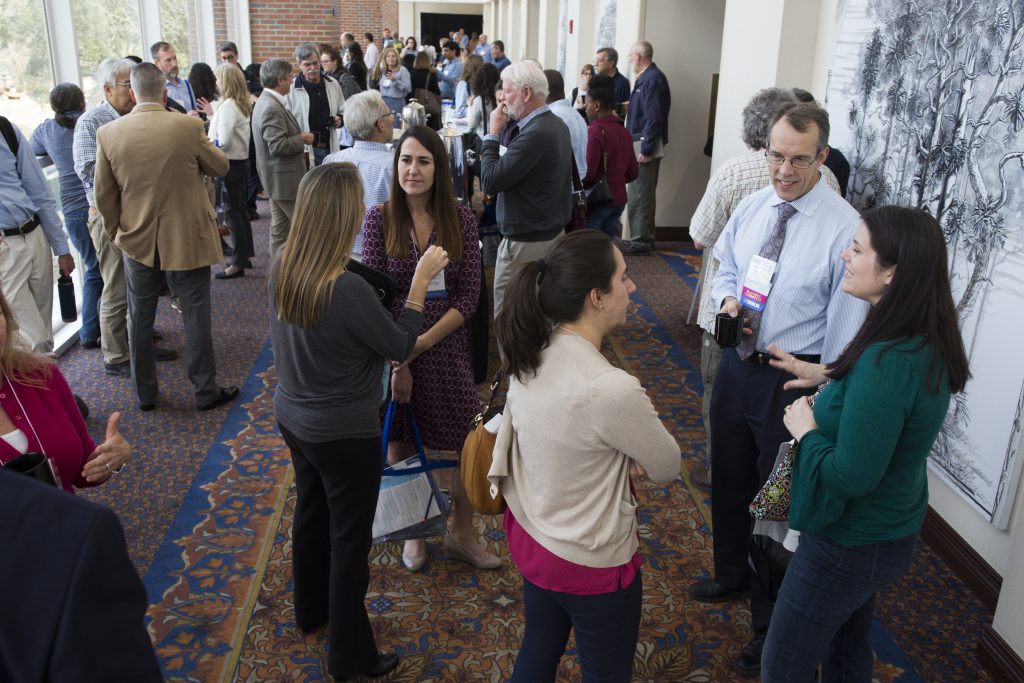 Symposium guests interacting in the North Hallway during break